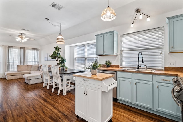 kitchen featuring hanging light fixtures, wooden counters, sink, and a wealth of natural light