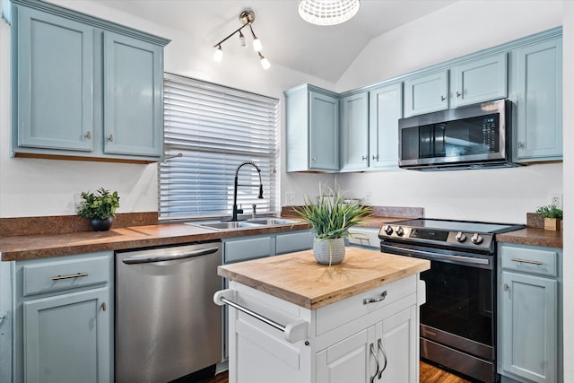 kitchen featuring stainless steel appliances, hardwood / wood-style flooring, sink, butcher block countertops, and vaulted ceiling