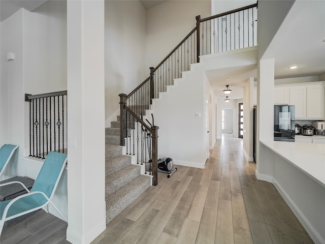 foyer entrance with light hardwood / wood-style floors and a towering ceiling