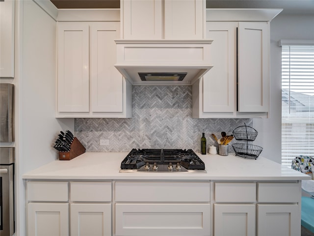 kitchen with tasteful backsplash, white cabinets, light stone counters, and stainless steel appliances