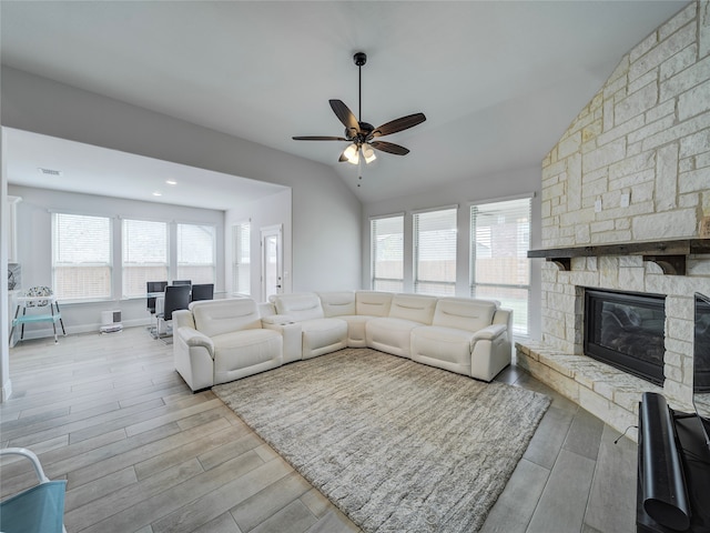 living room with a fireplace, a wealth of natural light, light hardwood / wood-style floors, and vaulted ceiling