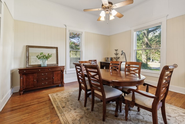 dining space with wood walls, hardwood / wood-style flooring, and ceiling fan