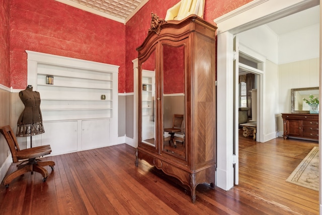 hall with hardwood / wood-style flooring, built in features, and a high ceiling