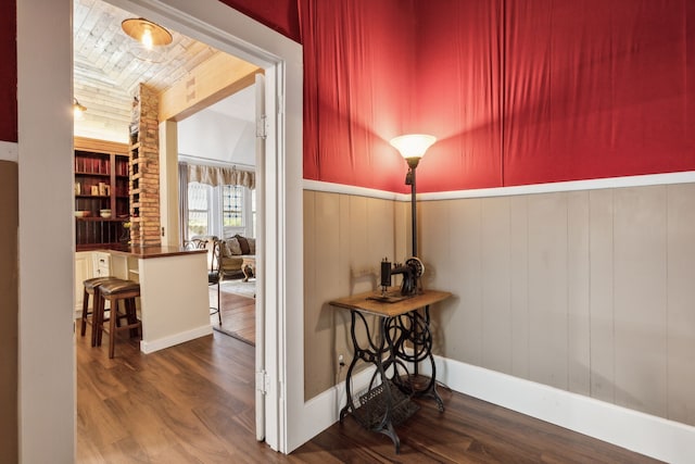 hallway featuring built in shelves, wood walls, dark hardwood / wood-style floors, and wooden ceiling