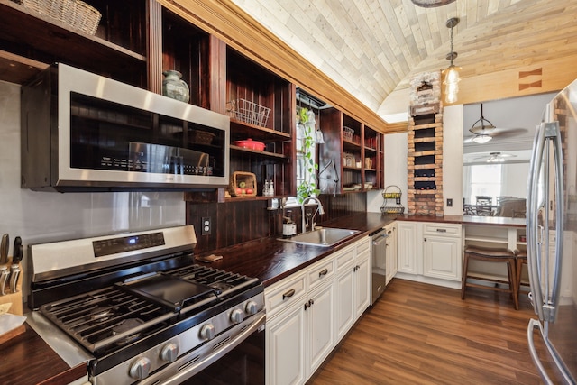 kitchen featuring white cabinetry, sink, appliances with stainless steel finishes, hanging light fixtures, and vaulted ceiling