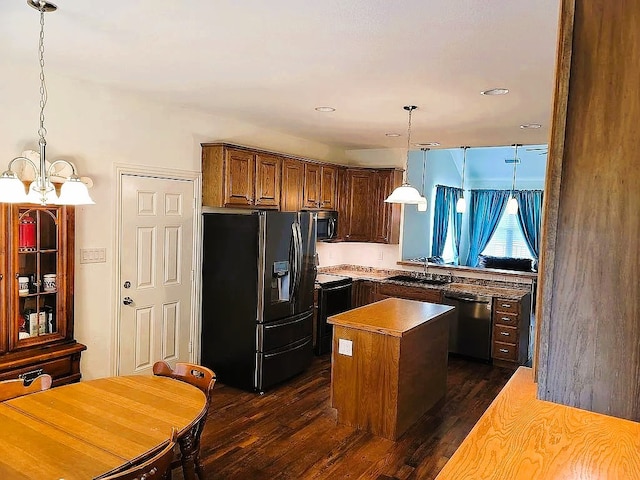 kitchen featuring sink, black appliances, dark hardwood / wood-style floors, hanging light fixtures, and a center island