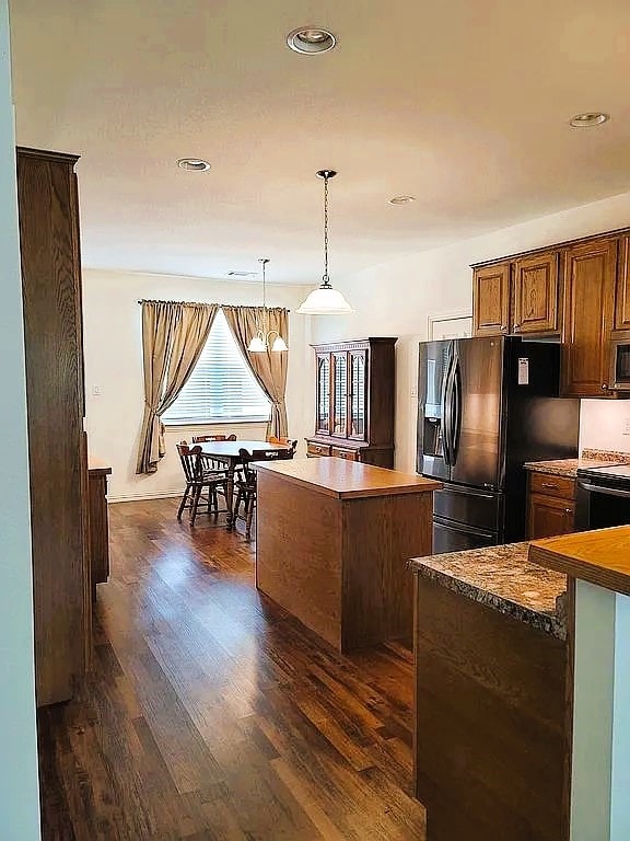 kitchen with dark wood-type flooring, hanging light fixtures, stainless steel appliances, and a center island