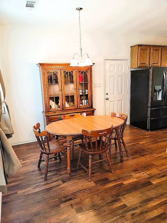 dining area featuring dark wood-type flooring and a chandelier