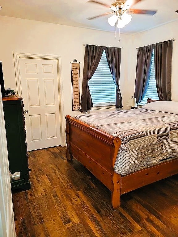 bedroom with dark hardwood / wood-style flooring and ceiling fan