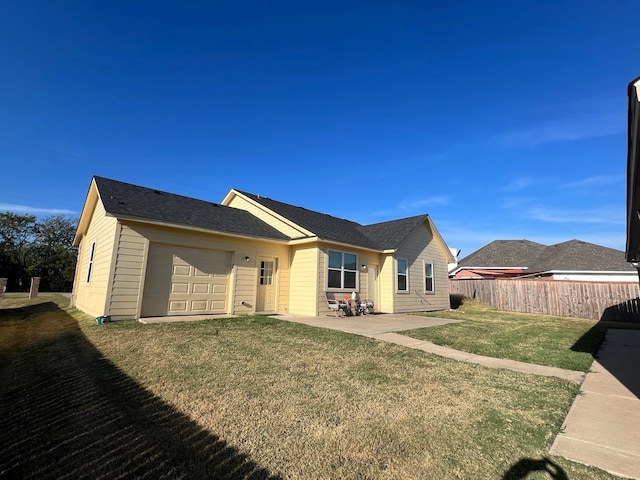 rear view of property with a garage and a lawn