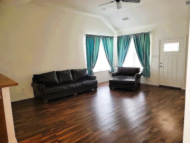 living room with a wealth of natural light, dark hardwood / wood-style floors, ceiling fan, and vaulted ceiling