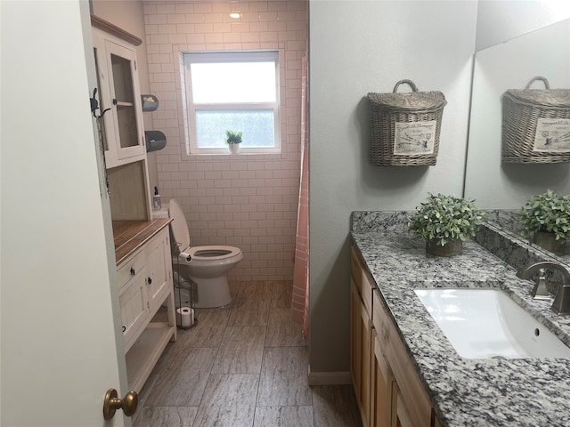 bathroom with tile walls, vanity, and toilet