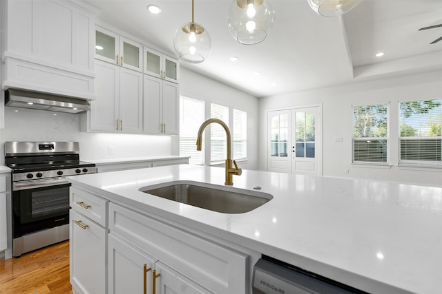 kitchen featuring stainless steel appliances, white cabinetry, sink, hanging light fixtures, and light wood-type flooring