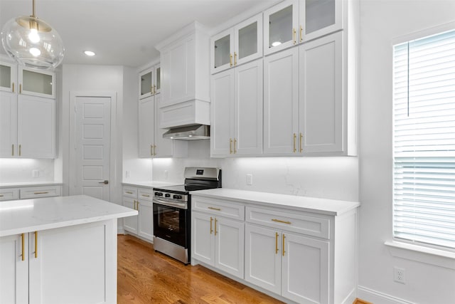 kitchen featuring light stone countertops, decorative light fixtures, stainless steel range oven, light hardwood / wood-style flooring, and white cabinets