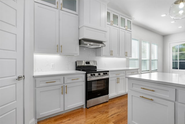 kitchen with white cabinets, stainless steel stove, light wood-type flooring, and decorative backsplash