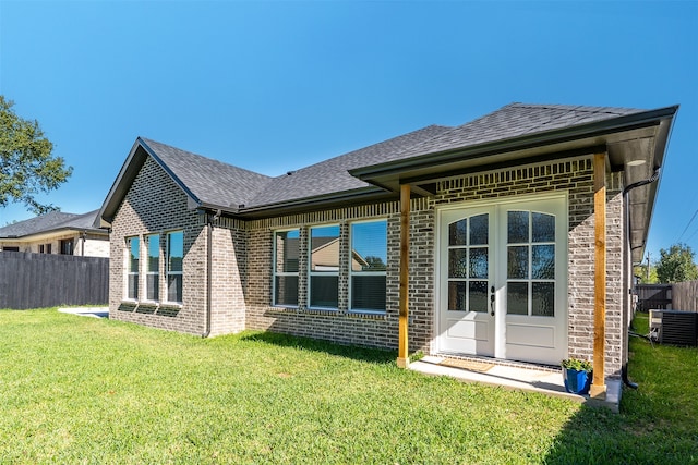 rear view of property featuring cooling unit and a yard