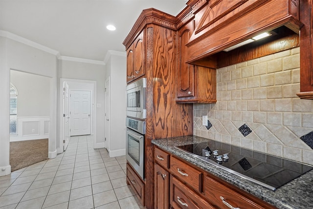 kitchen with dark stone countertops, backsplash, crown molding, and stainless steel appliances