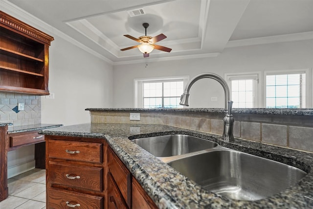 kitchen with dark stone counters, sink, a healthy amount of sunlight, and a raised ceiling