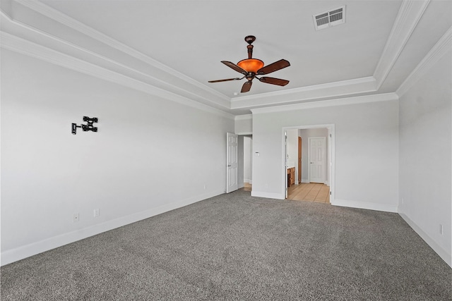 empty room featuring light colored carpet, a raised ceiling, and ornamental molding