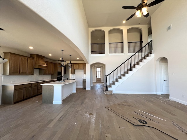 kitchen featuring sink, a kitchen island with sink, hardwood / wood-style floors, black electric cooktop, and decorative light fixtures