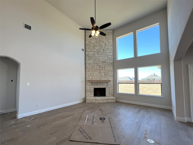 unfurnished living room with hardwood / wood-style floors, a fireplace, high vaulted ceiling, and ceiling fan