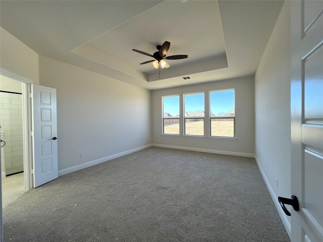 carpeted spare room with ceiling fan and a tray ceiling