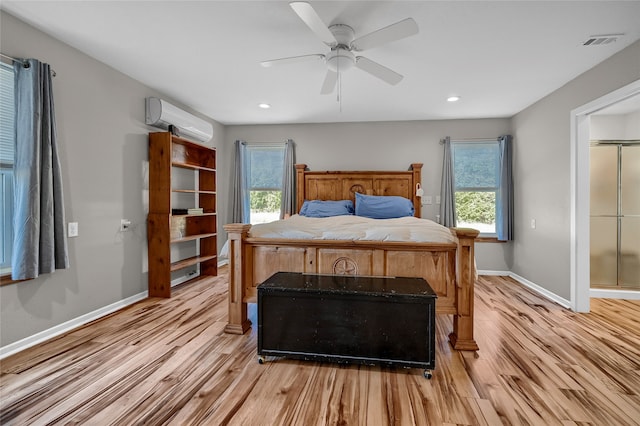 bedroom featuring a wall mounted AC, light hardwood / wood-style flooring, and ceiling fan