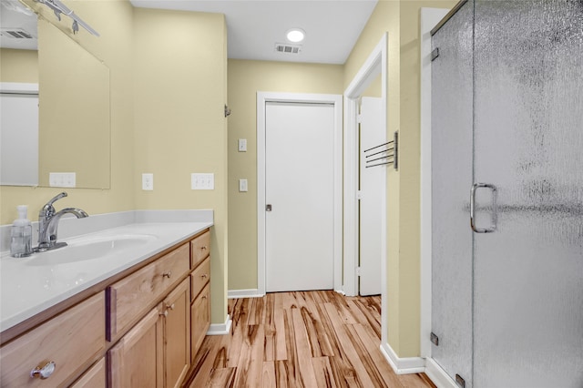 bathroom featuring vanity, an enclosed shower, and wood-type flooring