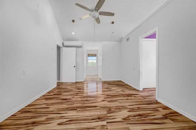 unfurnished room with a high ceiling, light wood-type flooring, a wall unit AC, and ceiling fan