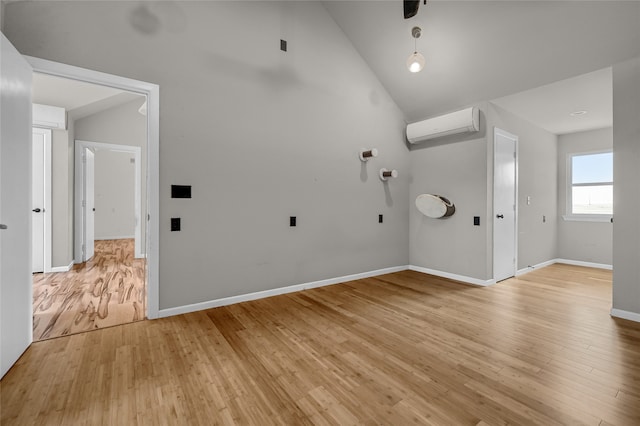 interior space with light hardwood / wood-style flooring, high vaulted ceiling, and a wall mounted air conditioner