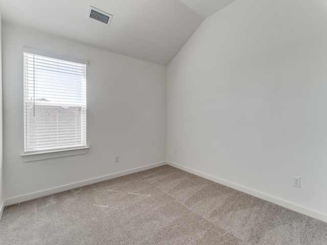 carpeted empty room with vaulted ceiling