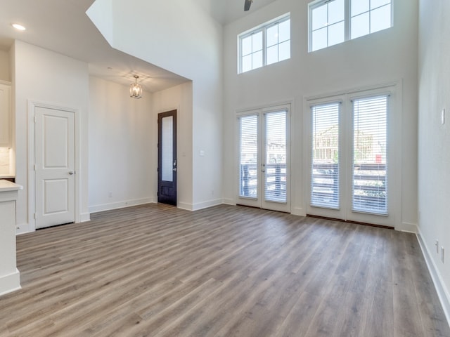 unfurnished living room featuring light hardwood / wood-style flooring, a high ceiling, and an inviting chandelier