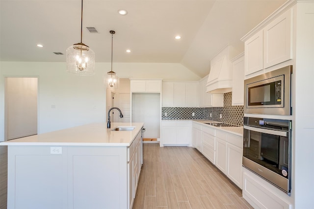 kitchen featuring white cabinets, appliances with stainless steel finishes, sink, and a kitchen island with sink