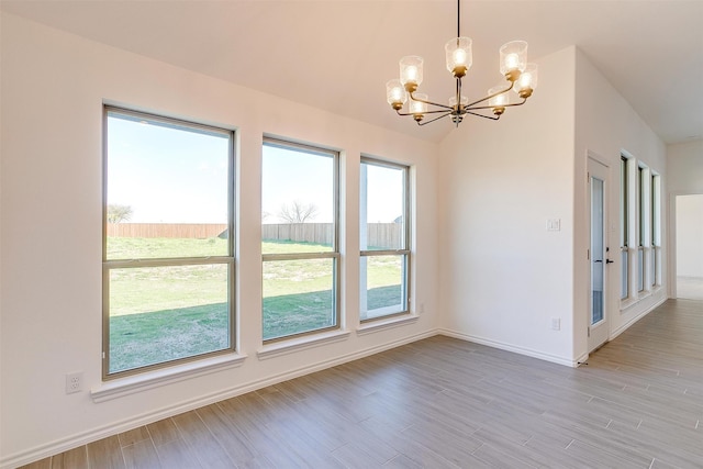 unfurnished room featuring light hardwood / wood-style flooring, a notable chandelier, and vaulted ceiling