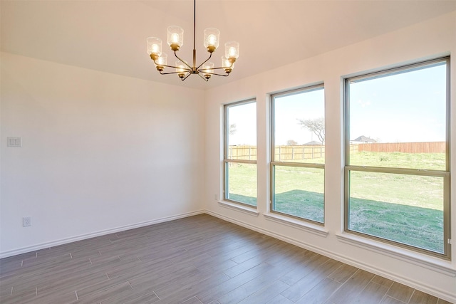 spare room featuring wood-type flooring and an inviting chandelier