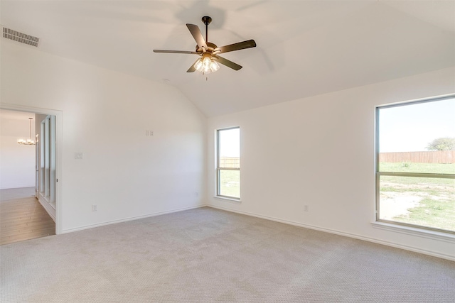 spare room with a wealth of natural light, light carpet, and vaulted ceiling