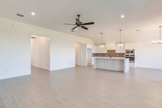 kitchen with stainless steel appliances, white cabinetry, an island with sink, and decorative light fixtures