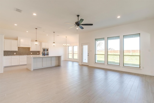 unfurnished living room featuring light wood-type flooring, ceiling fan with notable chandelier, and sink