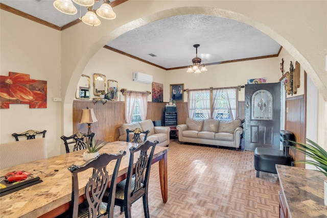 dining room with a wall unit AC, an inviting chandelier, a textured ceiling, ornamental molding, and parquet flooring