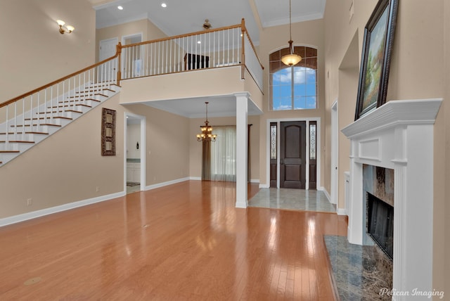 entryway with ornamental molding, hardwood / wood-style floors, a notable chandelier, and a high ceiling