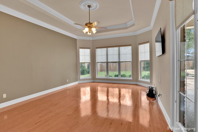 unfurnished room featuring hardwood / wood-style flooring, ornamental molding, ceiling fan, a raised ceiling, and french doors