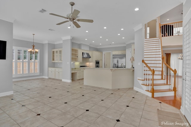 kitchen with ceiling fan with notable chandelier, built in refrigerator, kitchen peninsula, wall chimney exhaust hood, and crown molding