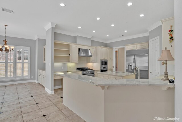 kitchen with appliances with stainless steel finishes, light stone countertops, wall chimney exhaust hood, light tile patterned floors, and backsplash