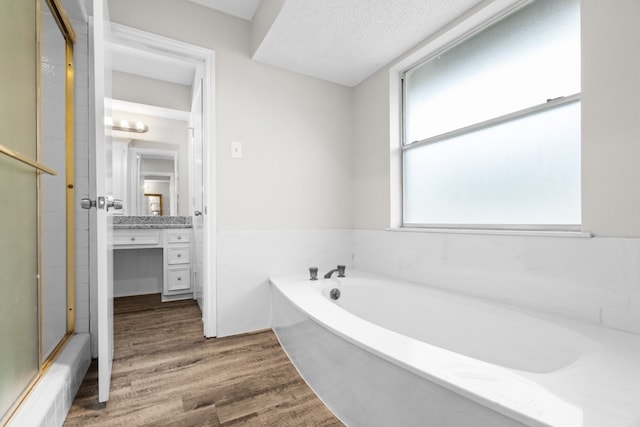 bathroom featuring independent shower and bath, vanity, wood-type flooring, and a textured ceiling