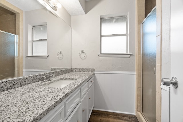 bathroom with vanity, walk in shower, wood-type flooring, and a textured ceiling