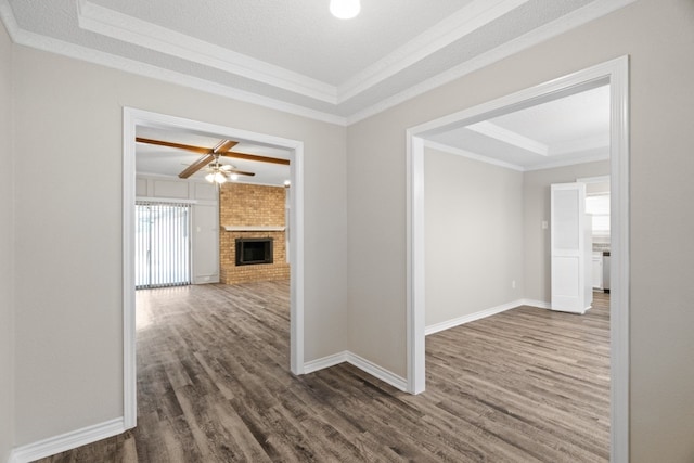 hallway with dark hardwood / wood-style floors, a textured ceiling, a raised ceiling, and ornamental molding