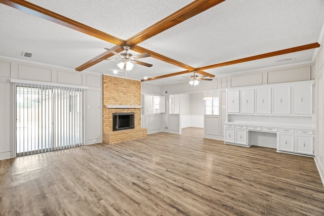 unfurnished living room featuring light wood-type flooring, a textured ceiling, ceiling fan, and beamed ceiling