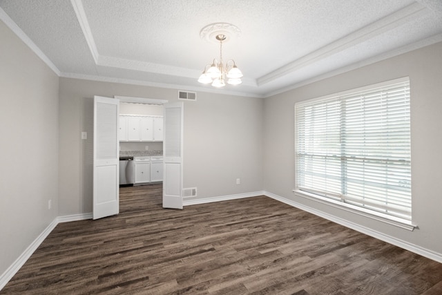 spare room featuring ornamental molding, dark hardwood / wood-style floors, a textured ceiling, an inviting chandelier, and a tray ceiling