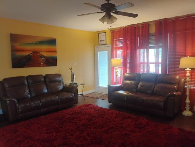 living area with baseboards and ceiling fan