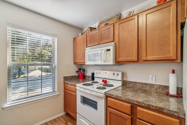 kitchen with light wood-type flooring, a textured ceiling, and white appliances